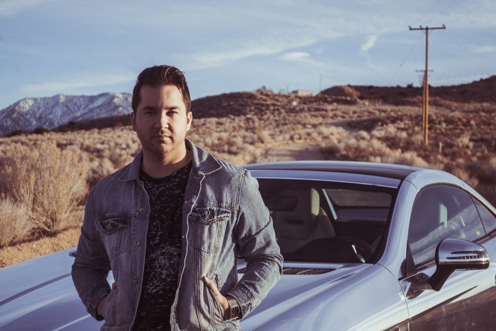 man sitting on someone else's car hood wondering about auto insurance coverage